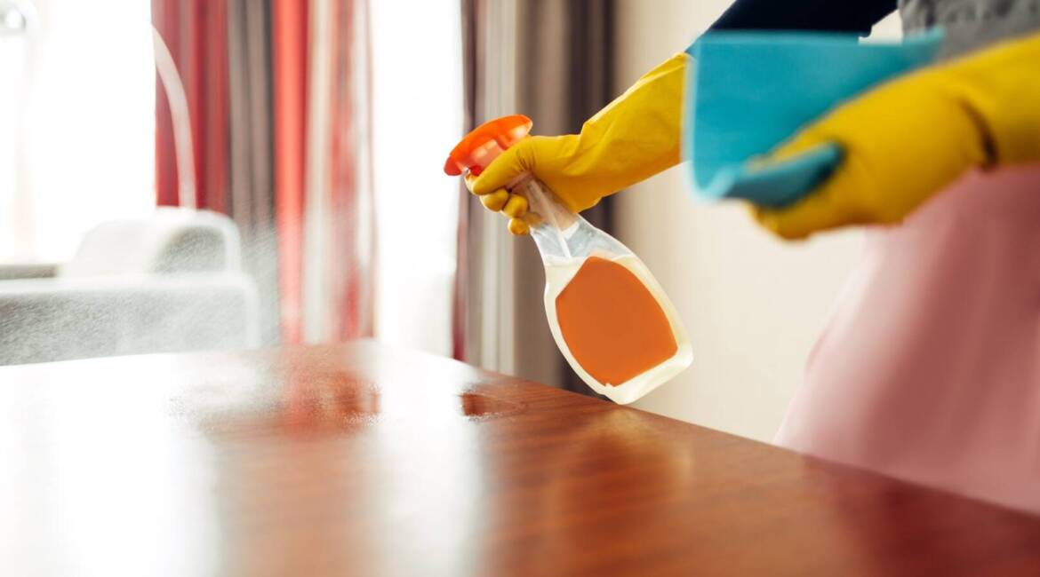 Housemaid hands cleans table with cleaning spray
